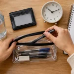 Student packing exam day supplies with pens water and clock